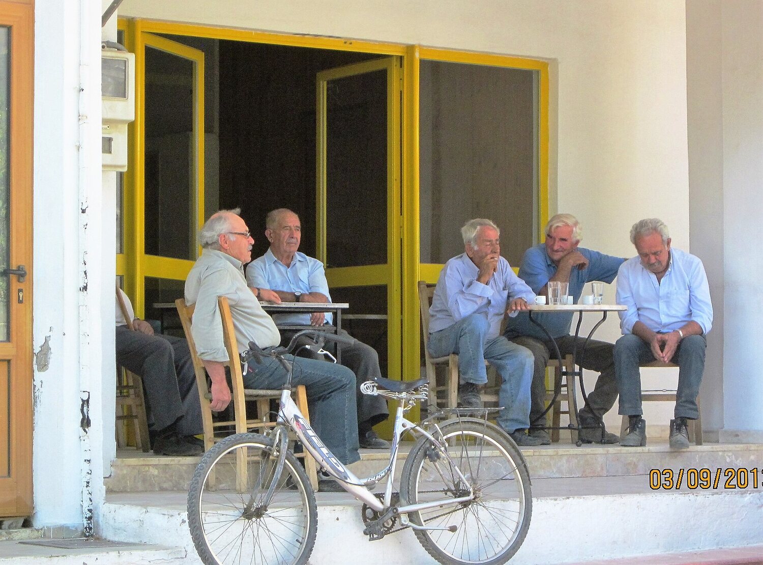 Ältere Männer sitzen vor einem Kafeneio auf Kreta und trinken Kaffee